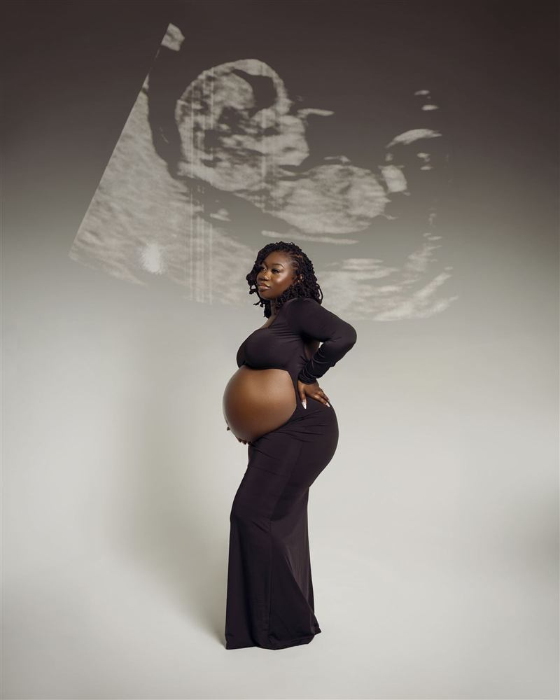 An expectant mother silhouetted before a projected sonogram image